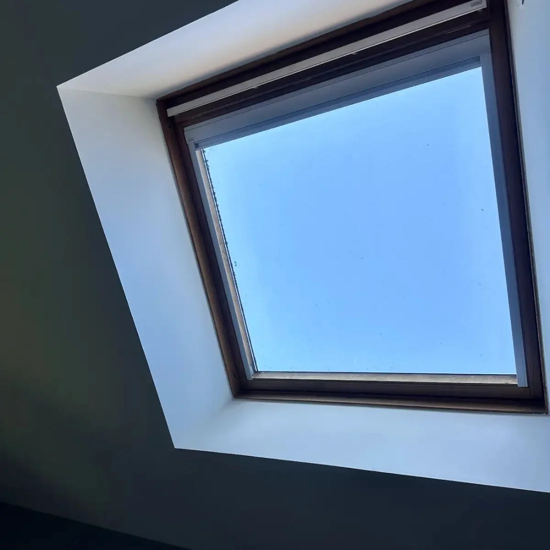 Ébrasement blanc d’une fenêtre de toit posée par Dim Toiture, vue en contre-plongée