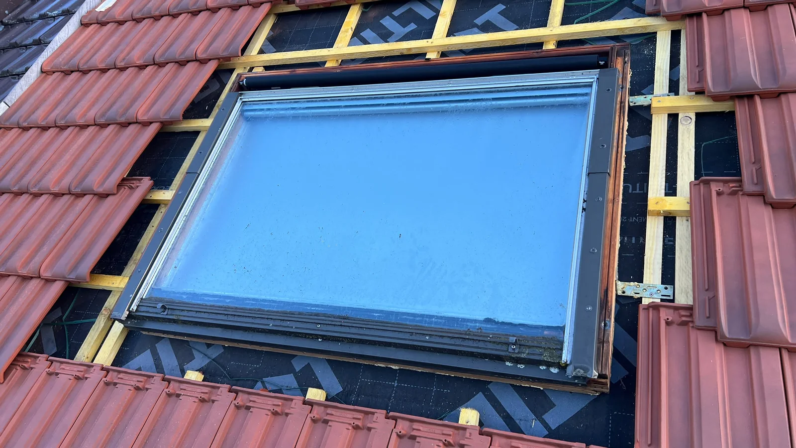 Fenêtre de toit Velux et son abergement d’étanchéité en cours de pose sur une toiture en tuiles à Cachan