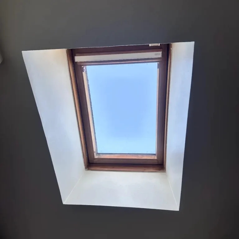 Fenêtre de toit vue depuis l’intérieur d’un comble aménagé, encadrement bois